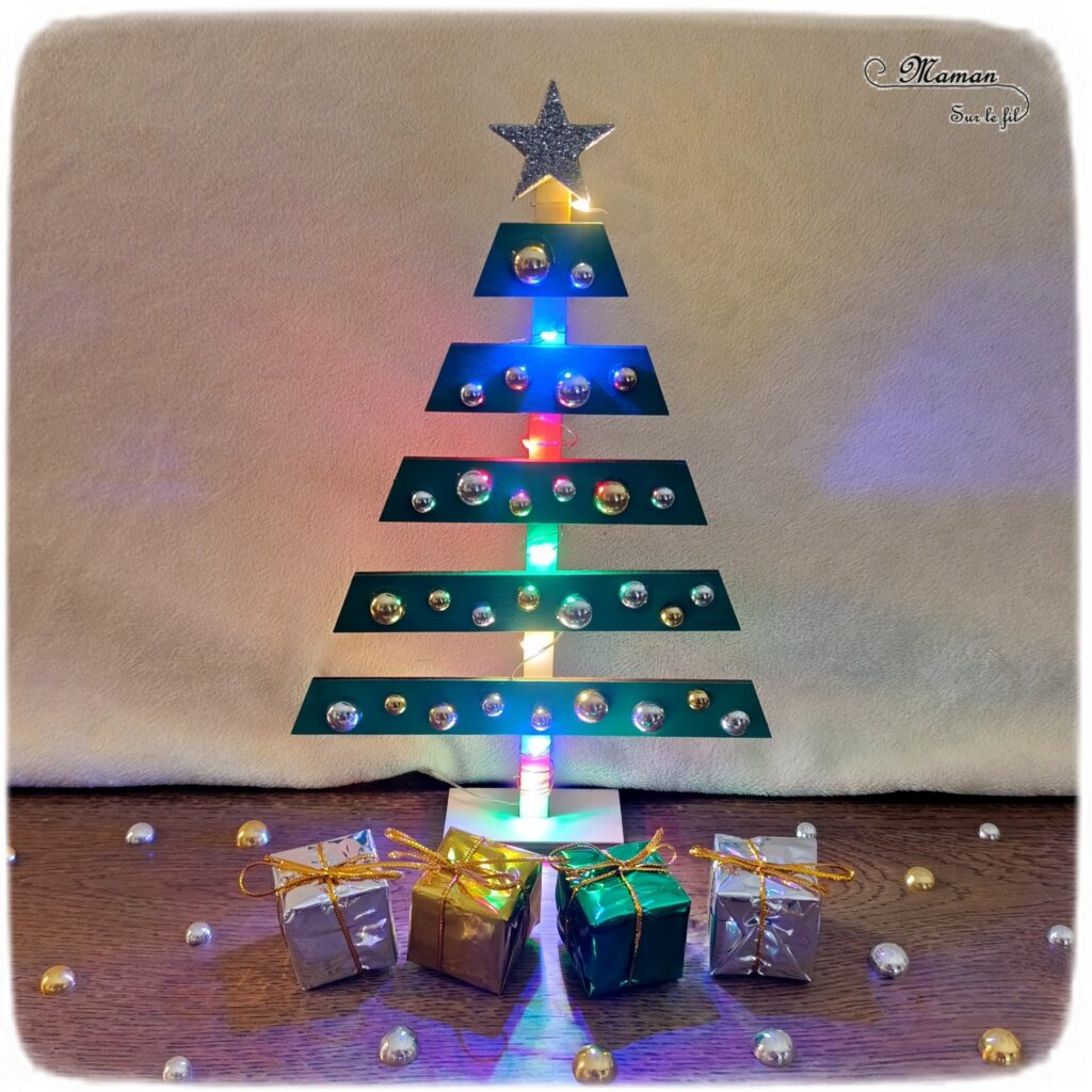 Fabriquer un sapin de Noël lumineux en bois : activité créative et manuelle enfants -Le tutoriel et tout le matériel vient de chez 10 Doigts - Sapin en bois, cabochons dorés et argentés, strass, peinture, mini cadeaux, guirlande lumineuse - Bricolage, DIY, décoration de Noël Fait maison - Kit tout compris - Thème Noël, hiver- Bricolage sympa et facile - Arts visuels Maternelle et cycle 2 - Maternelle et élémentaire - Créativité - Cycle 1 ou 2 - tutoriel photos - mslf