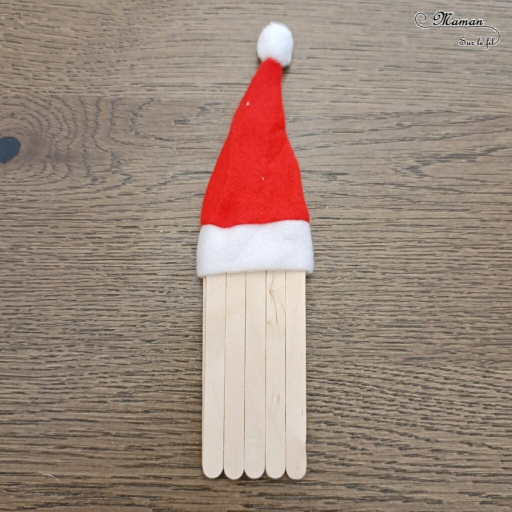 Fabriquer un Père Noël lumineux avec un gobelet : activité créative et manuelle enfants - Le tutoriel et tout le matériel viennent de chez 10 Doigts - Bricolage et décoration DIY réalisé à partir d'un gobelet, de bâtonnets de bois, de coton, d'un pompon rouge, de gommettes Yeux, d'un bonnet de Noël, de ruban en dentelle adhésif et d'une bougie LED - Bricolage Fait maison, décoration de Noël - Kit tout compris - Thème Noël, hiver, traditions - Bricolage sympa et facile - Arts visuels Maternelle et cycle 2 - Maternelle et élémentaire - Créativité - Cycle 1 ou 2 - tutoriel photos - mslf