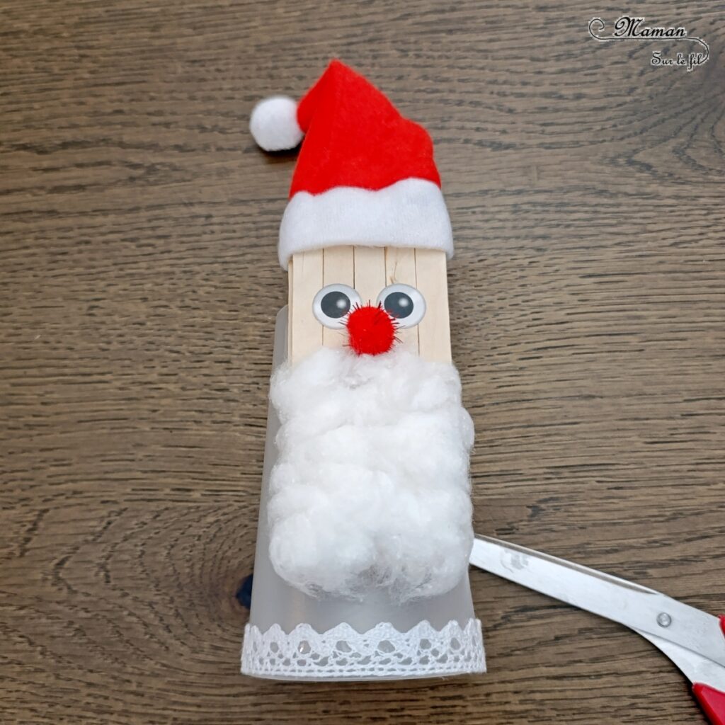 Fabriquer un Père Noël lumineux avec un gobelet : activité créative et manuelle enfants - Le tutoriel et tout le matériel viennent de chez 10 Doigts - Bricolage et décoration DIY réalisé à partir d'un gobelet, de bâtonnets de bois, de coton, d'un pompon rouge, de gommettes Yeux, d'un bonnet de Noël, de ruban en dentelle adhésif et d'une bougie LED - Bricolage Fait maison, décoration de Noël - Kit tout compris - Thème Noël, hiver, traditions - Bricolage sympa et facile - Arts visuels Maternelle et cycle 2 - Maternelle et élémentaire - Créativité - Cycle 1 ou 2 - tutoriel photos - mslf