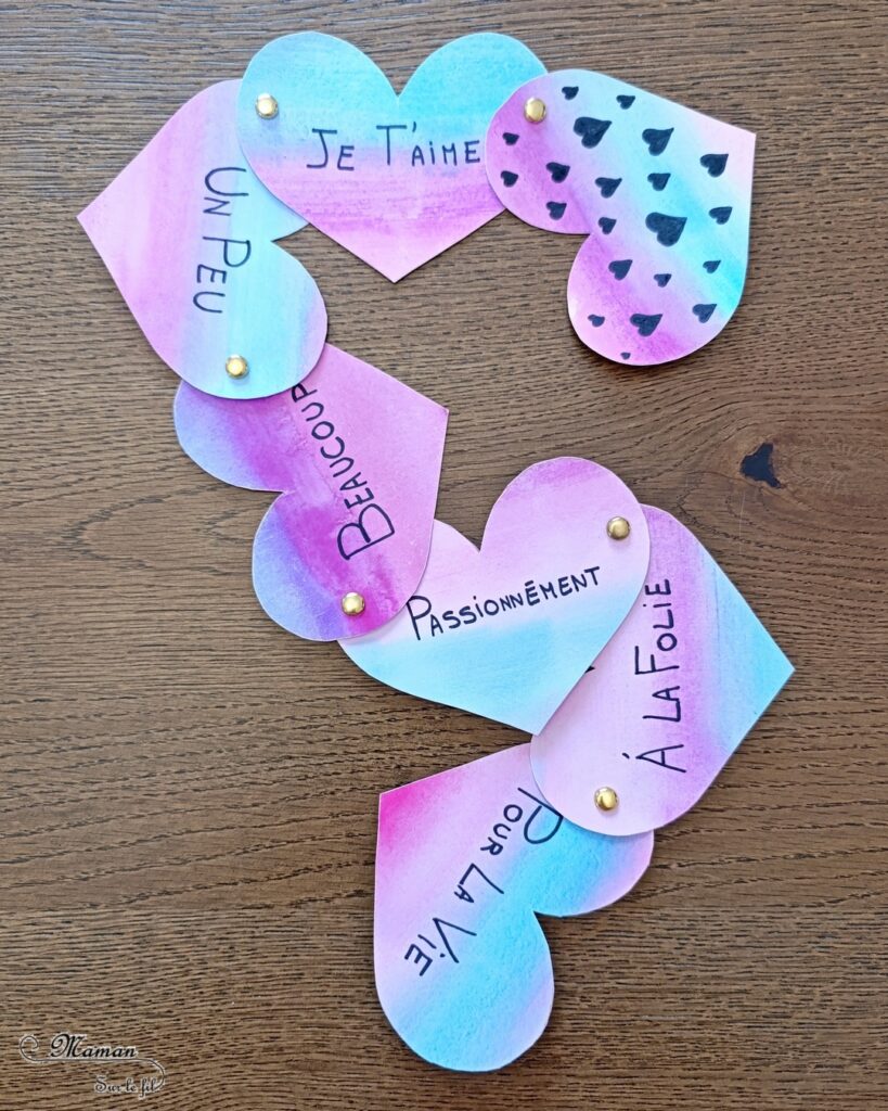 Fabriquer une carte Coeurs qui déroule à offrir : activité créative et manuelle enfants - Fond réalisé avec des bandes à la peinture type aquarelle - Découpage et écriture - Message Je t'aime un peu, beaucoup, à la folie... - Surprise DIY - Cadeau à offrir pour la Saint Valentin ou la fête des mères, pères, grands-mères, grands-pères... - Thème Amour, amitié, coeurs, Saint Valentin, fêtes - Bricolage et décoration sympa et facile - Arts visuels Maternelle et cycle 2 - Maternelle et élémentaire - Créativité - Cycle 1 ou 2 - tutoriel photos et vidéo - mslf